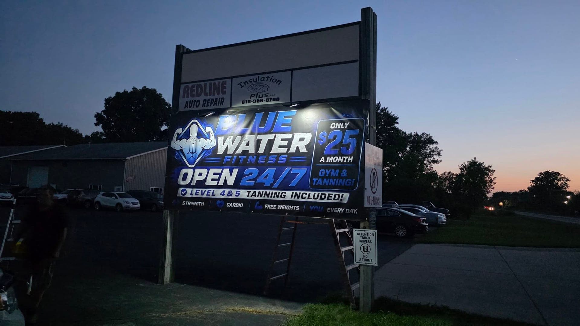 The Blue Water Fitness sign by the road on Dove Road at dusk