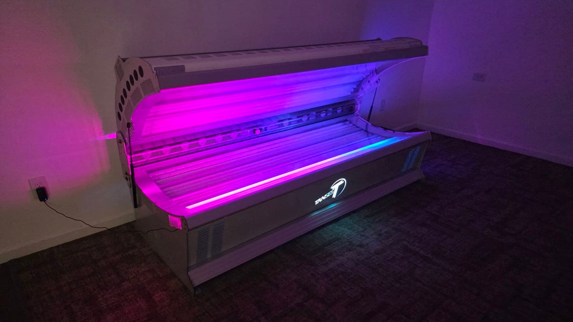 The Level 4 lay-down tanning bed at Blue Water Fitness, lit purple